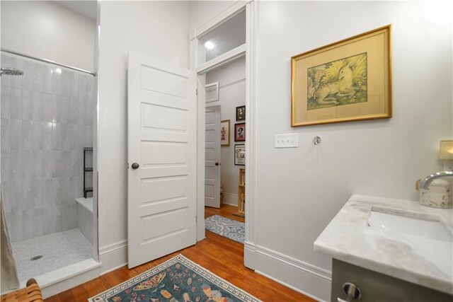 155 Alix St, New Orleans, LA 70114 - full bathroom with a tile shower, vanity, wood finished floors, and baseboards