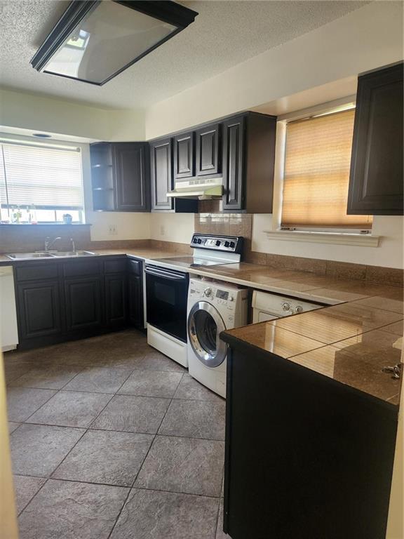 3711 Brandywine Dr Unit 3711, Metairie, LA 70002 - kitchen with electric stove, washer / dryer, under cabinet range hood, a sink, and dishwasher