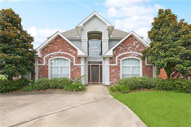4908 Avron Blvd, Metairie, LA 70006 - view of front facade featuring brick siding, stucco siding, a front lawn, and a shingled roof