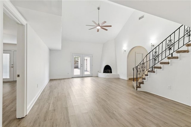 5117 Academy Dr, Metairie, LA 70003 - unfurnished living room with stairs, a ceiling fan, arched walkways, high vaulted ceiling, and light wood-type flooring