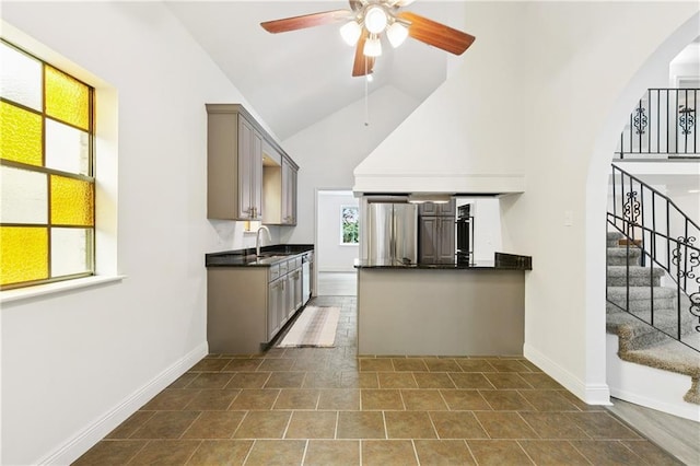 5117 Academy Dr, Metairie, LA 70003 - kitchen with dark countertops, a ceiling fan, high vaulted ceiling, gray cabinetry, and appliances with stainless steel finishes