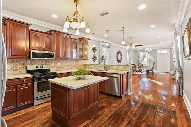 2720 New Orleans St, New Orleans, LA 70119 - kitchen featuring appliances with stainless steel finishes, a peninsula, ceiling fan, decorative backsplash, and glass insert cabinets