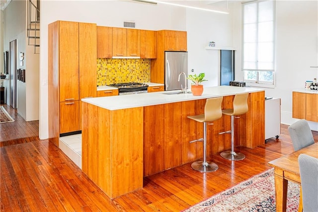 1260 Esplanade Ave Unit 2, New Orleans, LA 70119 - kitchen with appliances with stainless steel finishes, light wood-style floors, a sink, and decorative backsplash