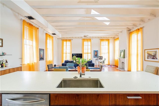 1260 Esplanade Ave Unit 2, New Orleans, LA 70119 - kitchen with dishwasher, open floor plan, beamed ceiling, a sink, and brown cabinets