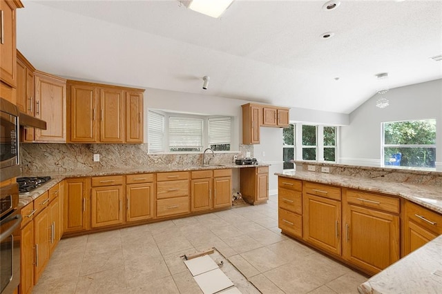 7218 Brookwood Dr, Mandeville, LA 70471 - kitchen featuring backsplash, a sink, light stone countertops, lofted ceiling, and brown cabinetry