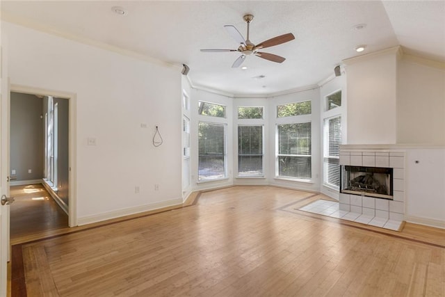 7218 Brookwood Dr, Mandeville, LA 70471 - unfurnished living room featuring a ceiling fan, light wood-type flooring, ornamental molding, a tiled fireplace, and baseboards