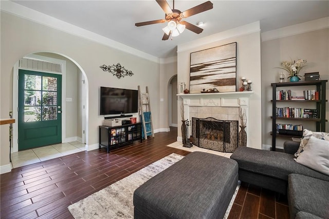 72158 Mill Rd, Abita Springs, LA 70420 - living room featuring arched walkways, a ceiling fan, wood tiled floors, a tile fireplace, and crown molding