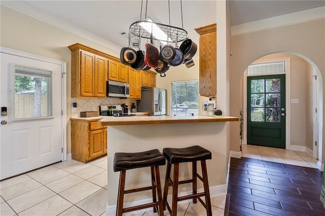72158 Mill Rd, Abita Springs, LA 70420 - kitchen with stainless steel appliances, arched walkways, a kitchen breakfast bar, decorative backsplash, and light countertops