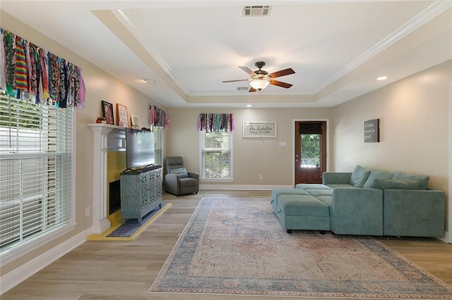 220 Canulette Rd, Slidell, LA 70458 - living room featuring a raised ceiling, light wood finished floors, ceiling fan, ornamental molding, and baseboards