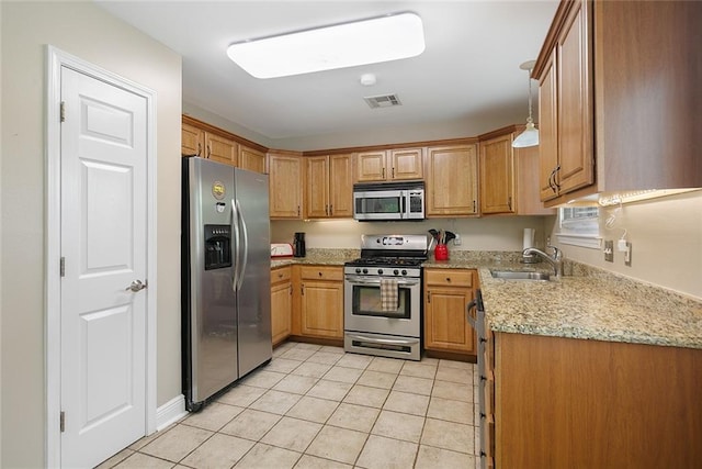 220 Canulette Rd, Slidell, LA 70458 - kitchen with stainless steel appliances, a sink, light tile patterned floors, brown cabinetry, and light stone counters