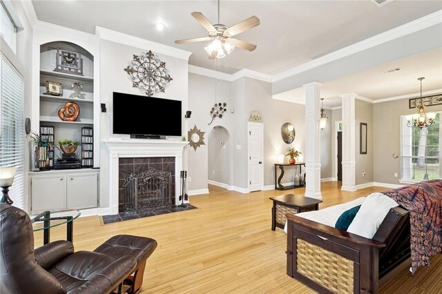 156 Egret St, Covington, LA 70433 - living area with light wood-type flooring, a tiled fireplace, ornate columns, a ceiling fan, and baseboards