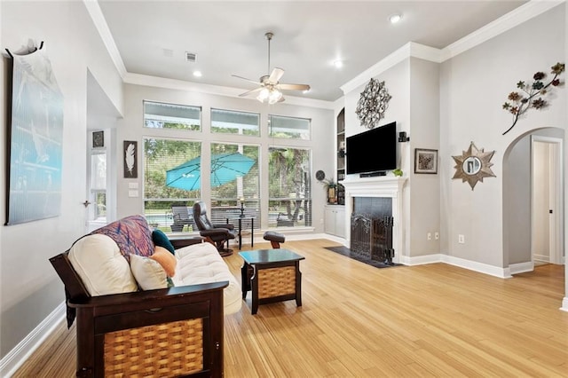 156 Egret St, Covington, LA 70433 - living area featuring arched walkways, ceiling fan, a tile fireplace, crown molding, and light wood-style floors