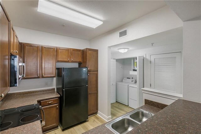 6765 Corporate Blvd Unit 11102, Baton Rouge, LA 70809 - kitchen featuring freestanding refrigerator, stainless steel microwave, separate washer and dryer, light wood-type flooring, and electric range oven