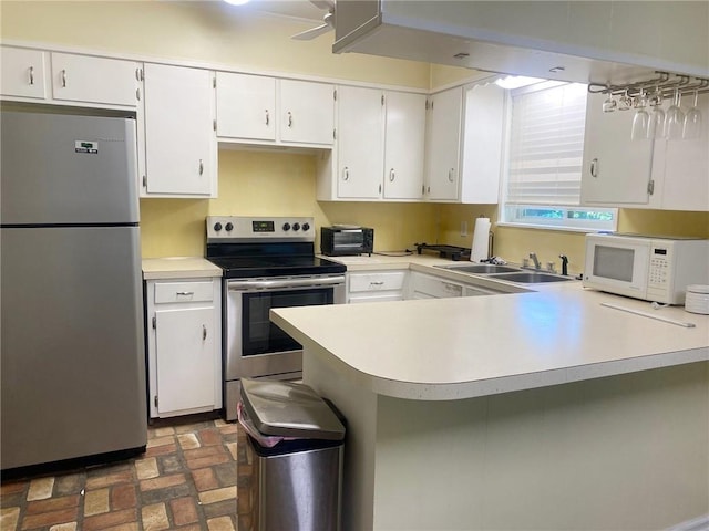 106 Matthews Dr, Slidell, LA 70458 - kitchen with stainless steel appliances, a sink, brick flooring, light countertops, and a peninsula