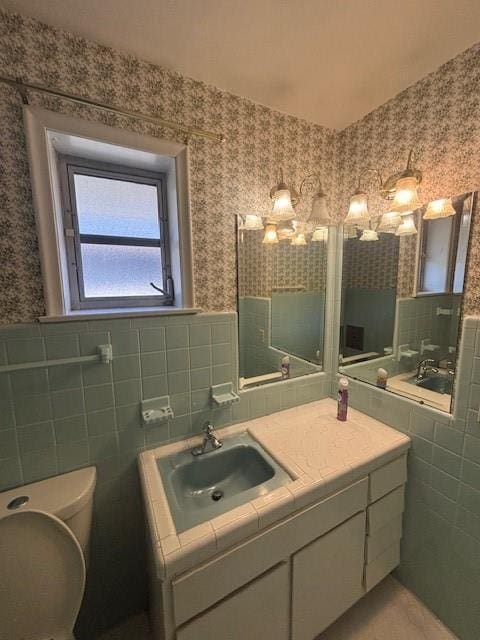 3107 Metairie Heights Ave, Metairie, LA 70002 - bathroom featuring wallpapered walls, tile walls, vanity, and toilet
