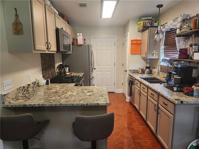 68 Camelia Trce, New Orleans, LA 70114 - kitchen featuring stainless steel appliances, a sink, a peninsula, a breakfast bar area, and light stone counters