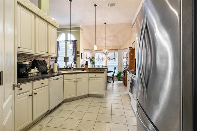 219 Bamboo Dr, Covington, LA 70433 - kitchen featuring appliances with stainless steel finishes, a peninsula, a chandelier, a sink, and light tile patterned floors