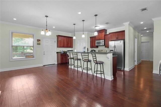 2634 Privateer Blvd, Barataria, LA 70036 - kitchen featuring stainless steel appliances, dark wood-style flooring, a kitchen bar, a kitchen island, and reddish brown cabinets