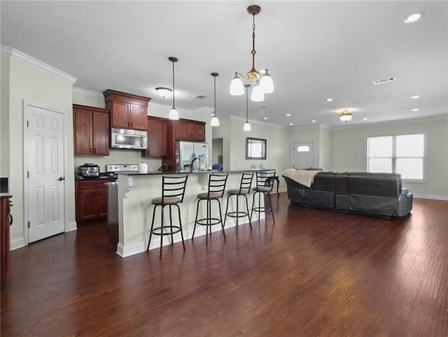 2634 Privateer Blvd, Barataria, LA 70036 - kitchen with appliances with stainless steel finishes, open floor plan, dark wood finished floors, a kitchen bar, and recessed lighting