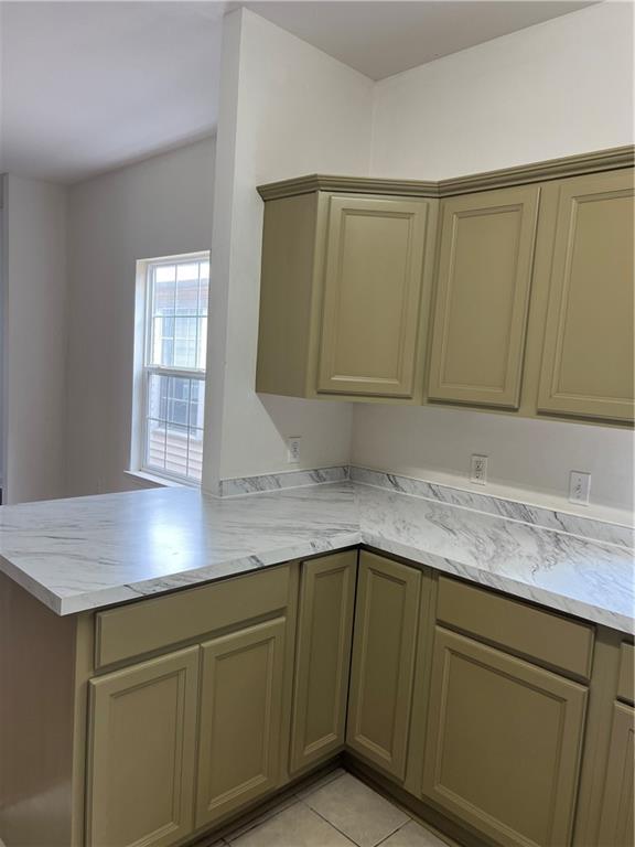 732 S Lopez St, New Orleans, LA 70119 - kitchen with a peninsula, light stone counters, and light tile patterned floors