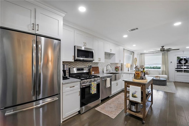 6208 Lafreniere St, Metairie, LA 70003 - kitchen featuring appliances with stainless steel finishes, a sink, light countertops, decorative backsplash, and white cabinetry