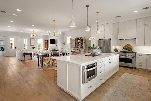 65 Hummingbird Rd, Covington, LA 70433 - kitchen featuring high quality appliances, ornamental molding, open floor plan, light countertops, and a chandelier