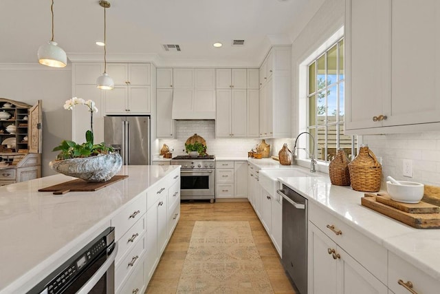 65 Hummingbird Rd, Covington, LA 70433 - kitchen featuring stainless steel appliances, a sink, white cabinets, light wood-style floors, and crown molding