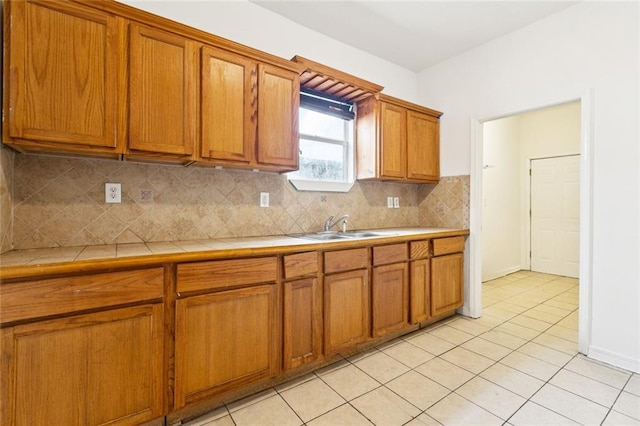 261315 N Prieur St, New Orleans, LA 70117 - kitchen featuring tile countertops, a sink, brown cabinetry, decorative backsplash, and light tile patterned flooring