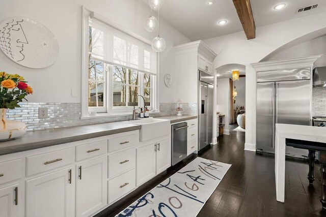 1322 S Jahncke Ave, Covington, LA 70434 - kitchen with appliances with stainless steel finishes, a sink, arched walkways, tasteful backsplash, and beamed ceiling