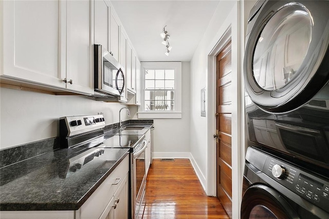 1530 Bordeaux St Unit C, New Orleans, LA 70115 - kitchen with appliances with stainless steel finishes, a sink, stacked washer and clothes dryer, baseboards, and wood finished floors