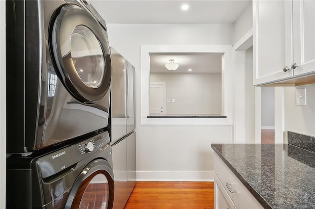1530 Bordeaux St Unit C, New Orleans, LA 70115 - laundry room featuring stacked washer and clothes dryer, baseboards, light wood-type flooring, cabinet space, and recessed lighting
