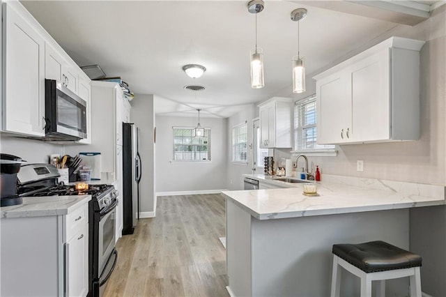 620 Maryland Ave, Metairie, LA 70003 - kitchen with stainless steel appliances, a sink, white cabinetry, light wood finished floors, and a peninsula