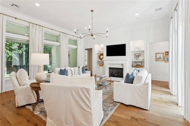 516 N Corniche Du Lac, Covington, LA 70433 - living room featuring a chandelier, built in shelves, light wood-type flooring, recessed lighting, and a fireplace