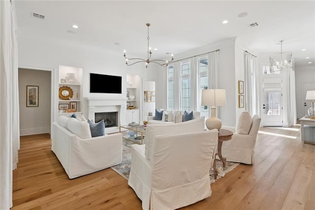 516 N Corniche Du Lac, Covington, LA 70433 - living area with a chandelier, built in shelves, crown molding, light wood finished floors, and recessed lighting