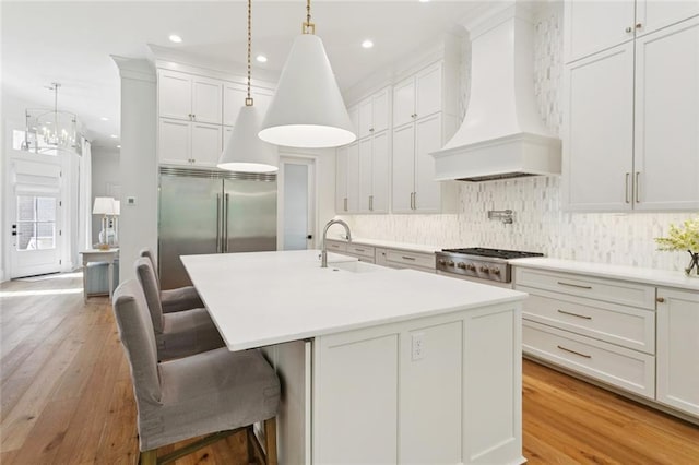 516 N Corniche Du Lac, Covington, LA 70433 - kitchen featuring premium range hood, a sink, tasteful backsplash, recessed lighting, and a kitchen island with sink