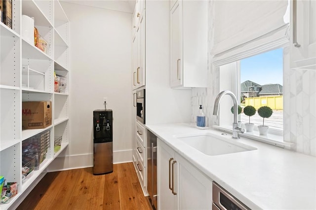 516 N Corniche Du Lac, Covington, LA 70433 - kitchen featuring light wood-type flooring, white cabinets, a sink, and light countertops
