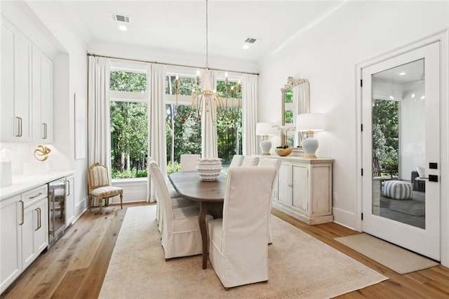 516 N Corniche Du Lac, Covington, LA 70433 - dining area with beverage cooler, plenty of natural light, light wood-type flooring, and ornamental molding