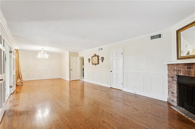 4909 Sunny Pl, Metairie, LA 70006 - unfurnished living room with a chandelier, a fireplace, a decorative wall, wood finished floors, and ornamental molding