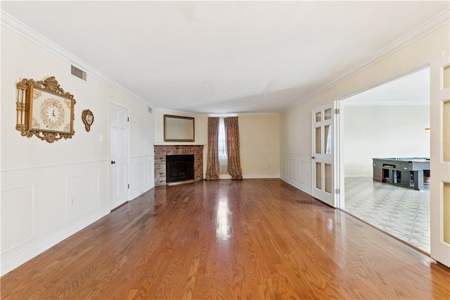 4909 Sunny Pl, Metairie, LA 70006 - unfurnished living room with wood finished floors, a fireplace, a decorative wall, ornamental molding, and a wainscoted wall