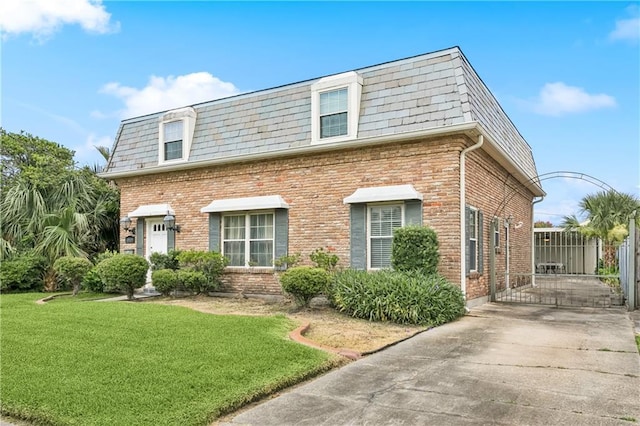 4909 Sunny Pl, Metairie, LA 70006 - view of front of property with mansard roof, a front yard, brick siding, a high end roof, and concrete driveway