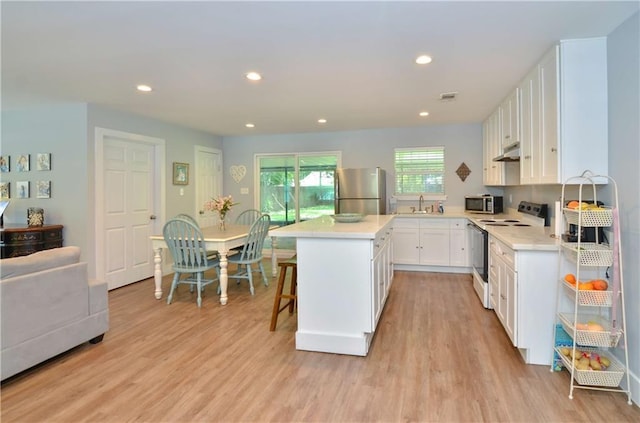 141 Audubon Dr, Mandeville, LA 70471 - kitchen featuring stainless steel appliances, light wood finished floors, under cabinet range hood, light countertops, and white cabinetry