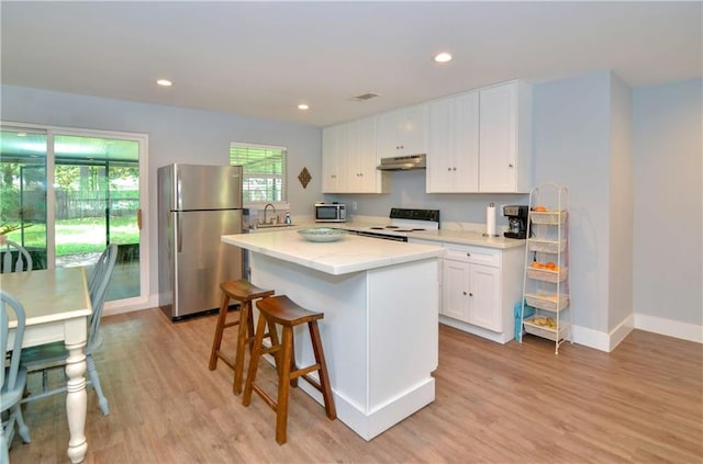 141 Audubon Dr, Mandeville, LA 70471 - kitchen featuring appliances with stainless steel finishes, under cabinet range hood, a sink, light wood-style flooring, and recessed lighting