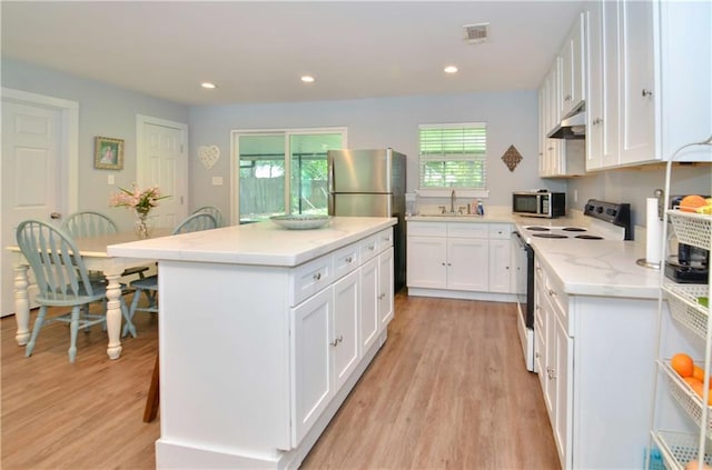 141 Audubon Dr, Mandeville, LA 70471 - kitchen featuring stainless steel appliances, under cabinet range hood, a sink, white cabinets, and recessed lighting