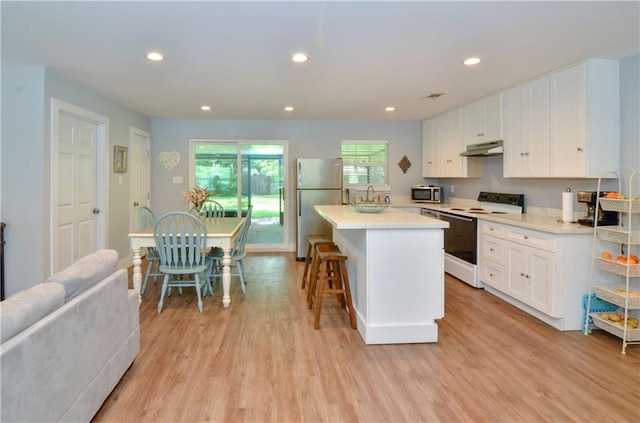 141 Audubon Dr, Mandeville, LA 70471 - kitchen with appliances with stainless steel finishes, under cabinet range hood, a kitchen island, white cabinetry, and light wood-style flooring
