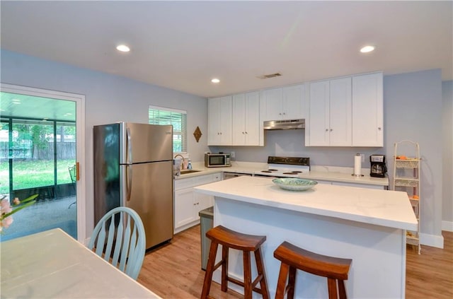 141 Audubon Dr, Mandeville, LA 70471 - kitchen with appliances with stainless steel finishes, under cabinet range hood, white cabinets, a breakfast bar, and recessed lighting