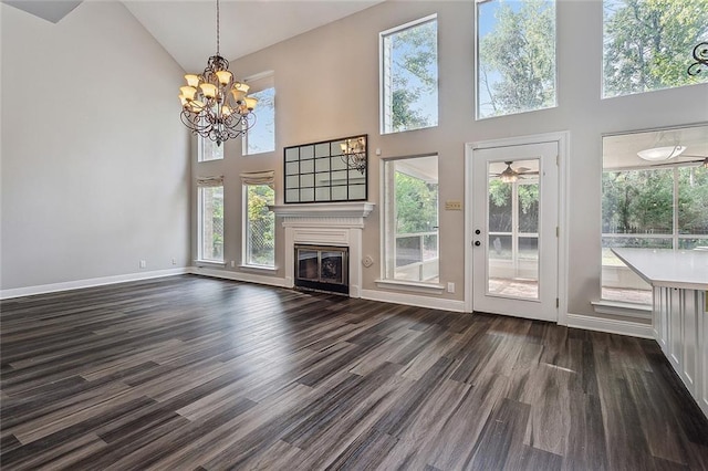 240 Silver Maple Dr, Mandeville, LA 70471 - unfurnished living room featuring high vaulted ceiling, a glass covered fireplace, dark wood-style floors, a chandelier, and plenty of natural light