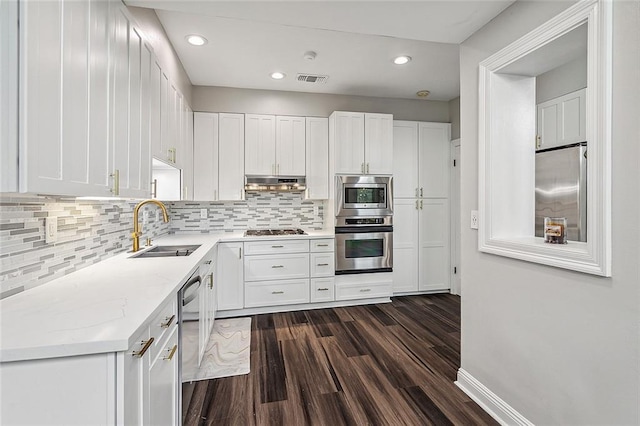 240 Silver Maple Dr, Mandeville, LA 70471 - kitchen featuring appliances with stainless steel finishes, a sink, dark wood finished floors, white cabinets, and backsplash