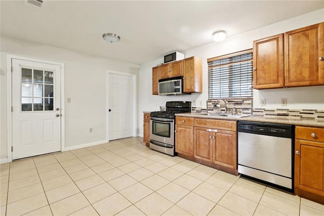 2716 Volpe Dr, Chalmette, LA 70043 - kitchen featuring stainless steel appliances, a sink, light tile patterned floors, brown cabinets, and light countertops
