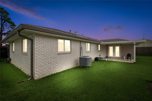 2716 Volpe Dr, Chalmette, LA 70043 - back of house at dusk with french doors, central AC unit, brick siding, and a patio