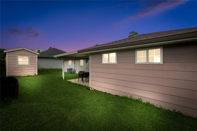 2716 Volpe Dr, Chalmette, LA 70043 - yard at dusk with central air condition unit, a lawn, and an outbuilding